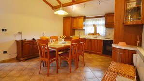 Een keuken met houten kastjes, een eettafel met stoelen en een hanglamp.