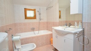 Een badkamer met bad, toilet, wastafel en spiegel.