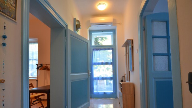 Ein Flur mit einem Holztisch, einer blauen Tür und einem Fenster mit Vorhängen.