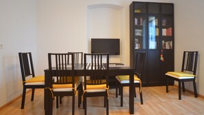 Ein Essbereich mit Tisch, Stühlen, einem Fernseher und einem Bücherregal.