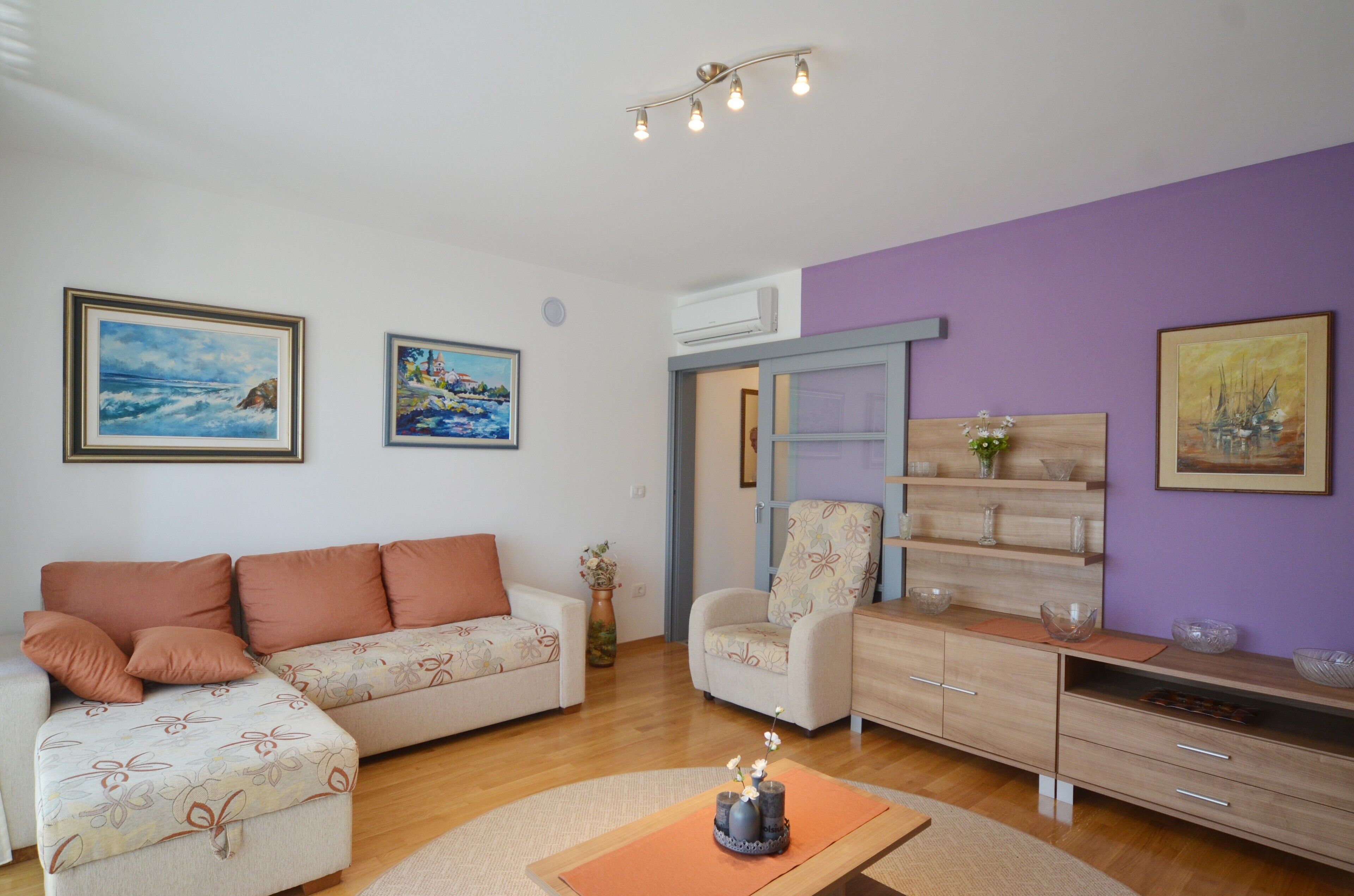 Sala de estar com sofá, poltrona e mesa de centro com objetos decorativos.