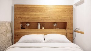 Ein Schlafzimmer mit einem hölzernen Kopfteil, einem Bett mit weißer Bettwäsche und einem Regal mit Dekorationen.