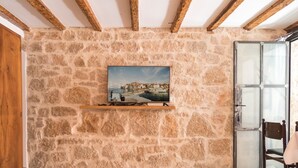 Eine Steinsäule mit einem angebrachten Fernseher, Holzbalken und einer Glastür.