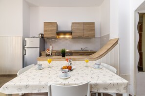 Een kleine keuken met houten kastjes, een inbouwfornuis en een ontbijt klaar tafel.