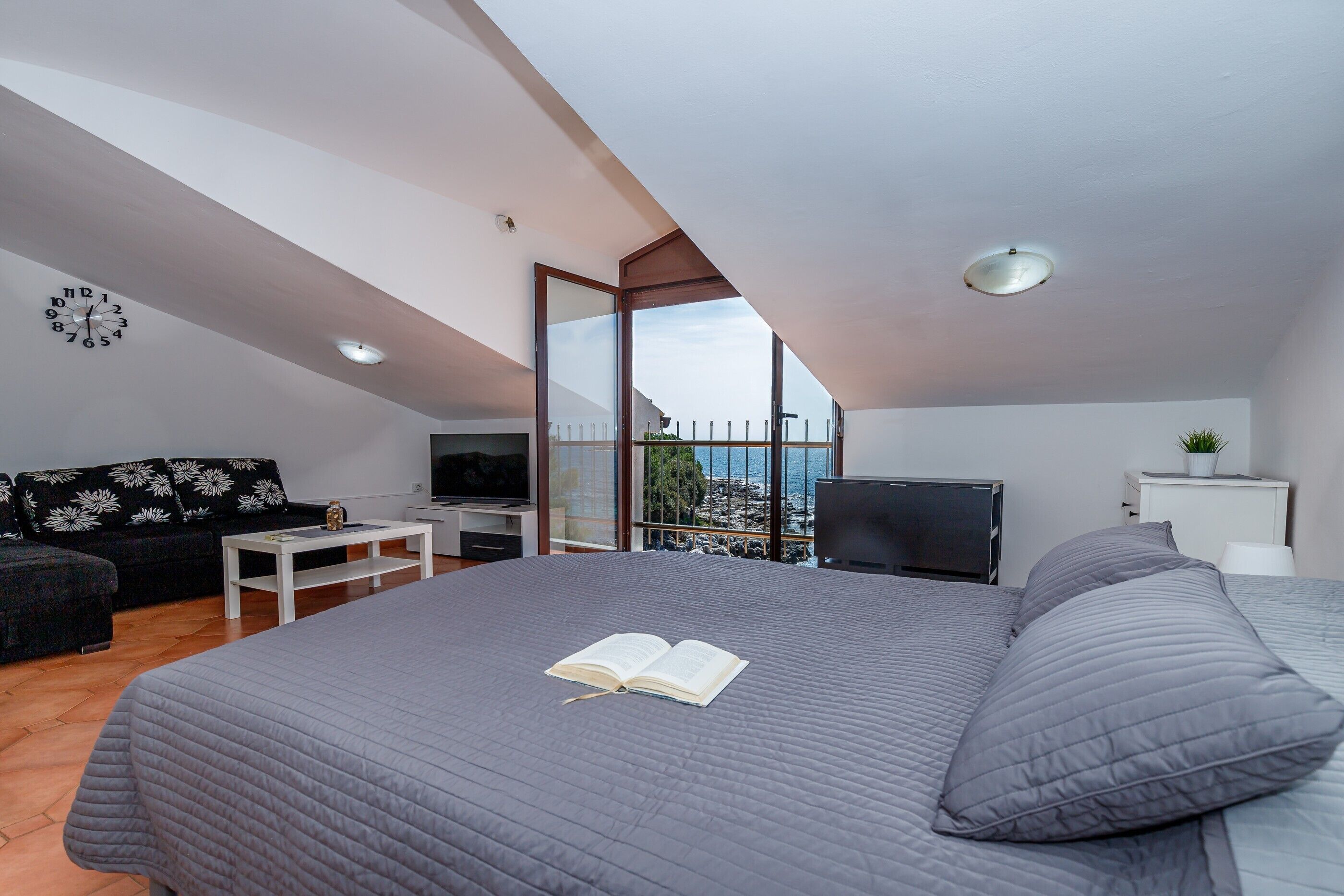 Une chambre dotée d’un grand lit, d’une télévision, d’un canapé et d’un balcon avec vue.