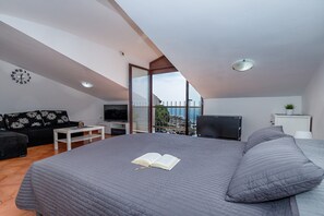 Ein Schlafzimmer mit einem großen Bett, einem Fernseher, einer Couch und einem Balkon mit Blick.