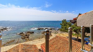A coastal view with a clear sky, rocky shoreline, and tiled roofs. - Cuvi Beach - Mansarde Apartment (Rovinj)