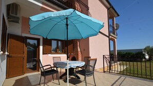 A patio with a table and chairs, an umbrella, and a brick oven. - Orbanic Valalta Apartment 1 (Rovinj)