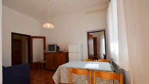 A small, compact kitchen with a dining table, chairs, a refrigerator, and a television. - Orbanic Valalta Apartment 1 (Rovinj)