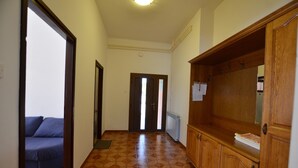 A hallway with a tiled floor, a wooden cabinet, and a blue sofa. - Orbanic Valalta Apartment 1 (Rovinj)