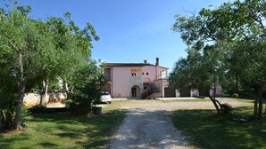A two-story building with a stone facade, a central entrance, and a gravel driveway leading to a parked car. - Orbanic Valalta Apartment 2 (Rovinj)