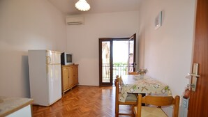 A small, compact room with a kitchenette, a dining table with chairs, and a sliding glass door leading to an outdoor area. - Orbanic Valalta Apartment 2 (Rovinj)
