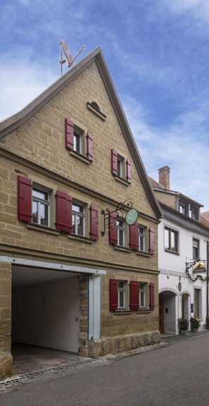 A two-story building with red shutters, a visible garage door, and a chimney.