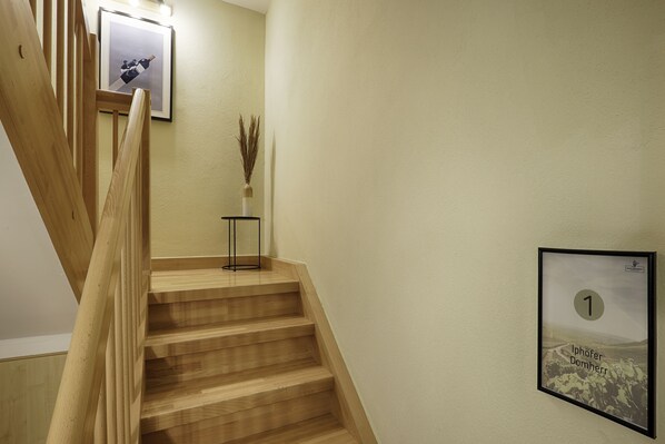 Una escalera de madera con un cuadro en la pared y una mesita con un florero.