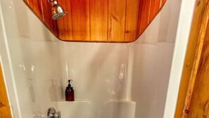 Eine Dusche mit Holztür und weiß gefliesten Wänden.