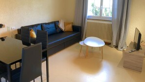 Ein modernes Wohnzimmer mit einer schwarzen Couch, einem weißen Tisch und einem Fernsehschrank.