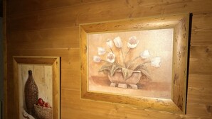 Zwei gerahmte Gemälde an einer Holzwand.