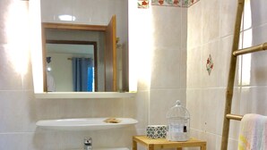 Ein Badezimmer mit einem weißen Waschbecken, einem Spiegel und einer Holzhängeschrank mit Handtüchern.