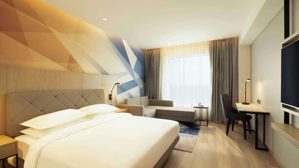 Una habitación de hotel moderna con una cama grande, un sofá, un escritorio y un televisor.