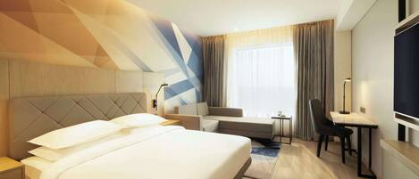 Una habitación de hotel moderna con una cama grande, un sofá, un escritorio y un televisor.