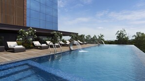A modern hotel with a swimming pool, lounge chairs, and a wooden deck. - Hyatt Place Bharuch (Bharuch)