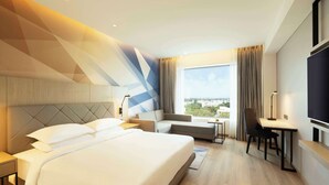 Una habitación de hotel con una cama grande, un sofá, un escritorio y un televisor.