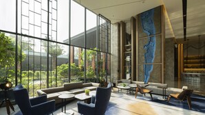 A modern lounge area with large windows, comfortable seating, and a decorative wall. - Hyatt Place Bharuch (Bharuch)
