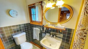 A bathroom with a toilet, sink, and mirror.