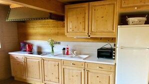 Eine Küche mit Holdekor-Schränken, einer weißen Arbeitsplatte, einer Kaffeemaschine, einem Toaster und einem Kühlschrank.