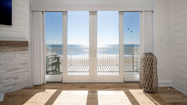 Ein Zimmer mit einer großen Schiebetür, die auf einen Balkon mit Meerblick führt.
