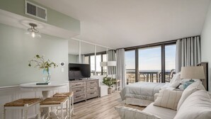 Un salon moderne comprenant un canapé, un téléviseur et un coin repas avec une table et des chaises.