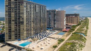 Un hôtel de grande hauteur, avec de nombreux étages, une piscine et une vue sur la plage.
