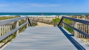 Une promenade en bois qui mène à une plage offrant une vue dégagée sur l’océan.