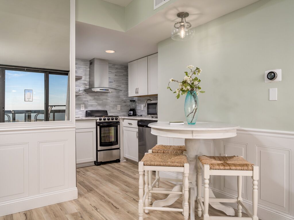 A modern kitchen with white cabinetry, a round dining table, and two bar stools.