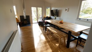 A spacious kitchen with a wooden table and bench, a built-in stove, and a large window offering a view of the outdoors. - Drummond (Aberfeldy)
