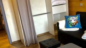 Een kleine kamer met een kast, een bed, een tafeltje en een kussen met een tijgerprint.