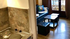 Een keuken met een fornuis en een wastafel, een eethoek met een tafel en stoelen, en een balkon met uitzicht.