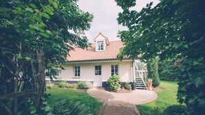 A two-story house with a red-tiled roof, a front porch, and a garden with ferns and shrubs. - Fermette Les Ormes - Cottage 8 people in Merlimont village (Merlimont)