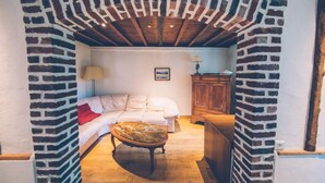 A cozy room with a brick archway, a bed, a wooden cabinet, and a lamp. - Fermette Les Ormes - Cottage 8 people in Merlimont village (Merlimont)