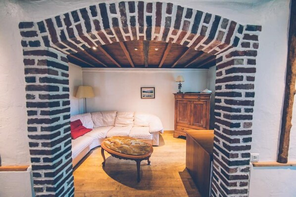 A cozy room with a brick archway, a bed, a wooden cabinet, and a lamp.