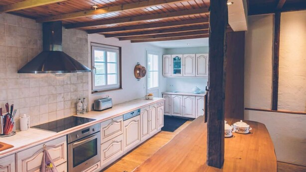 A kitchen with white cabinets, a wooden countertop, a built-in oven, and a black range hood. - Fermette Les Ormes - Cottage 8 people in Merlimont village (Merlimont)