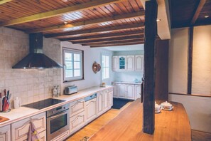 A kitchen with white cabinets, a wooden countertop, a built-in oven, and a black range hood. - Fermette Les Ormes - Vacation Home for 8 People in the Village of Merlimont (Merlimont)