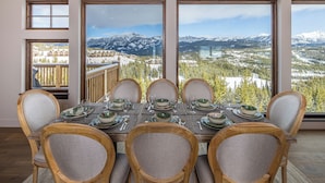 A dining table set for six with a mountain view through large windows.