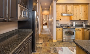 A kitchen with granite countertops, stainless steel appliances, and wooden cabinets. - Gorgeous Home Right in Town Center! Fitness Center! 15 Min Drive to Resort! (Big Sky)