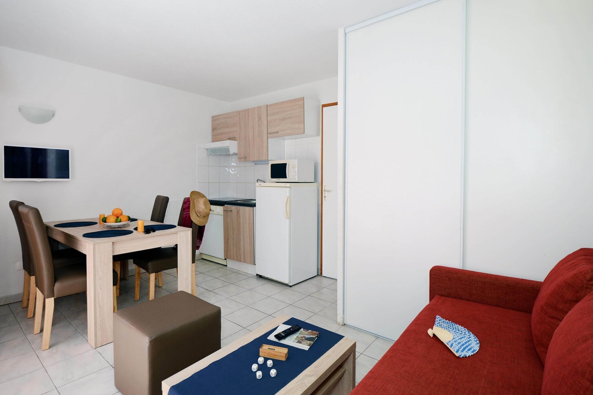 A compact living space with a dining area, kitchenette, and a red sofa.