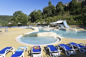Ein Poolbereich mit Liegestühlen, einer Wasserrutsche und einem Bergpanorama.