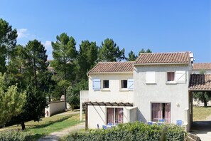 A two-story building with a tiled roof, a covered patio area, and a small garden. - Cozy Apartment with Terrace (Vallon Pont D Arc)