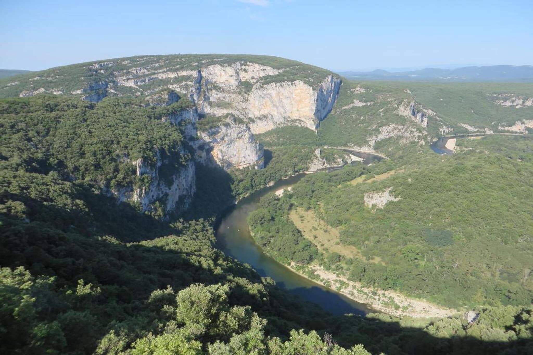 A river winding through a mountainous landscape with cliffs and dense greenery.