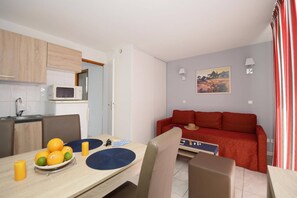 A compact living space with a kitchenette, dining area, and a red sofa.