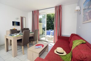 A modern living room with a red sofa, a coffee table, a dining area with chairs, and a TV mounted on the wall. - Cozy Apartment with Terrace (Vallon Pont D Arc)